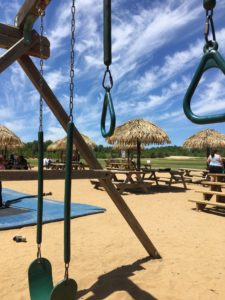 Site extérieur de L'École de parachute Voltige Aménagement accueillant pour les clients de Parachute Voltige, avec tables à pique-nique, parasols et jeux pour enfant.