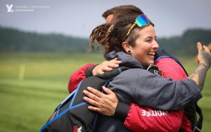 Une instructrice de parachute tandem fait un câlin à son passager juste après l’atterrissage.